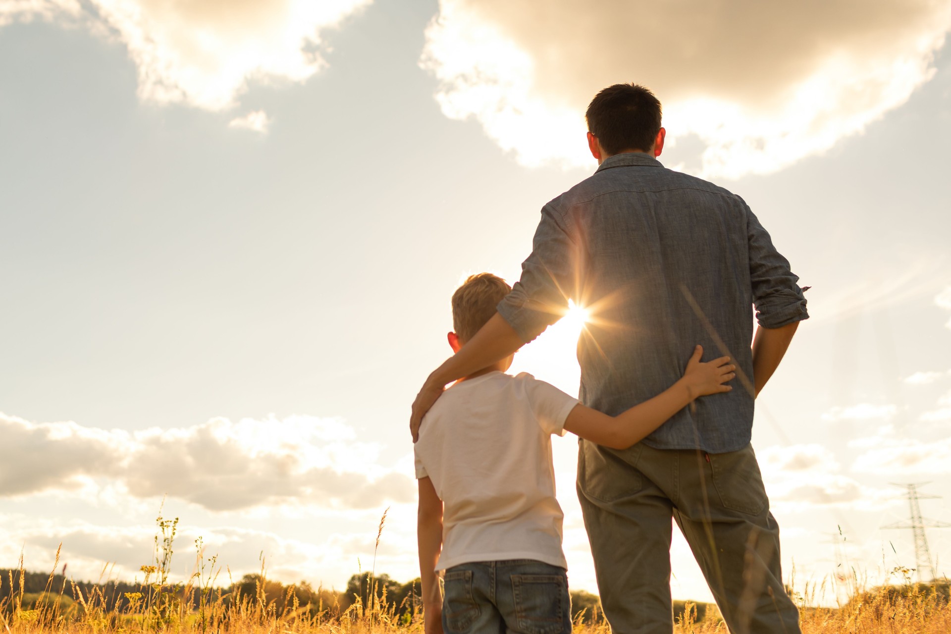 Father and son watching beautiful sunset together.